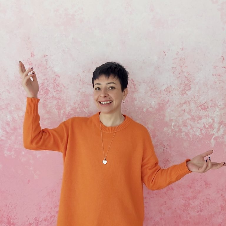 İnci Varol Ünlü, turuncu kıyafetiyle bir teraste yoga hareketi sırasında